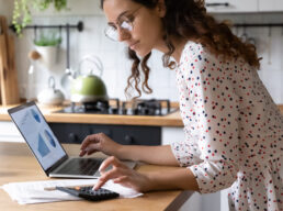 Serious woman wearing glasses calculating finances, working with project statistics