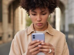 woman-reads-sms-message-smartphone-browses-wireless-internet-dressed-casual-brown-jacket-poses-outside-uses-software-app_273609-54772